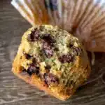 Close-up of a Zucchini Chocolate Chip Muffin broken open showing the moist brown butter sour cream crumb with melted chocolate chips and zucchini shreds