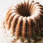 A slice of Apple Cider Cake showing the moist warm-spiced brown sugar crumb with apple cider cream cheese frosting on a white plate
