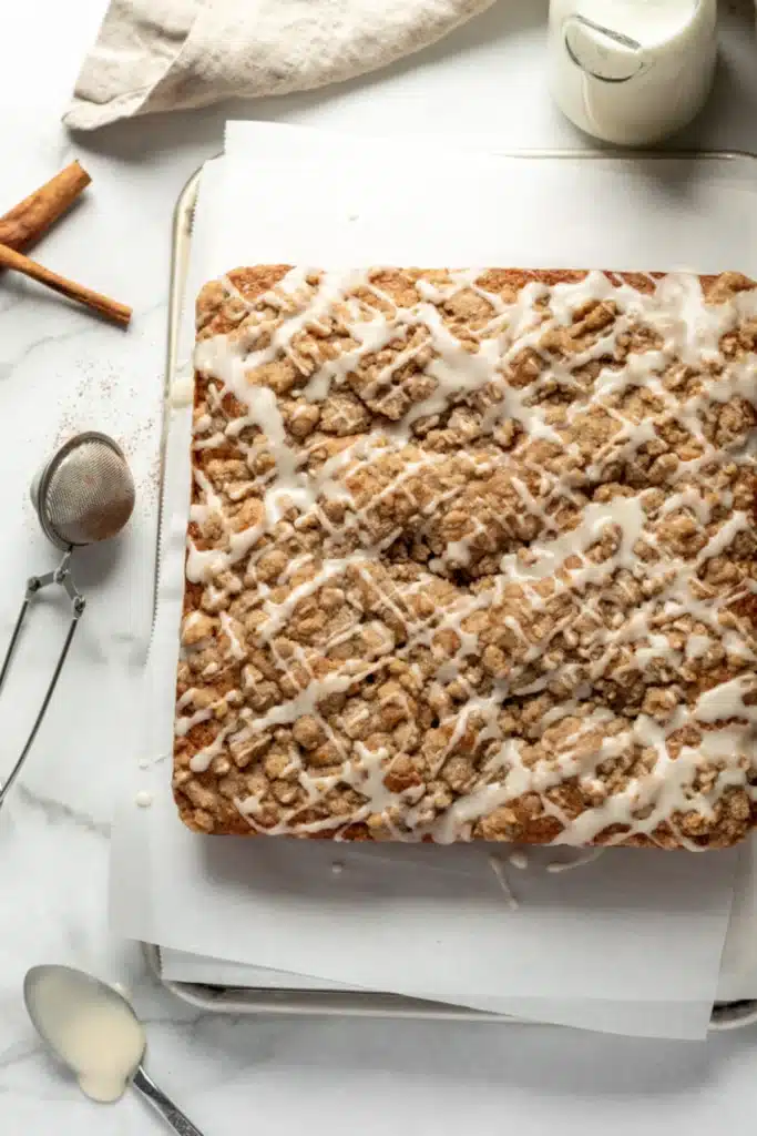 Home 4 Apple Cider Coffee Cake Recipe stunning fall brunch coffee cake with gorgeous cream cheese swirl layer and golden brown sugar streusel topping cut to show the swirl cross-section in a white pan on marble