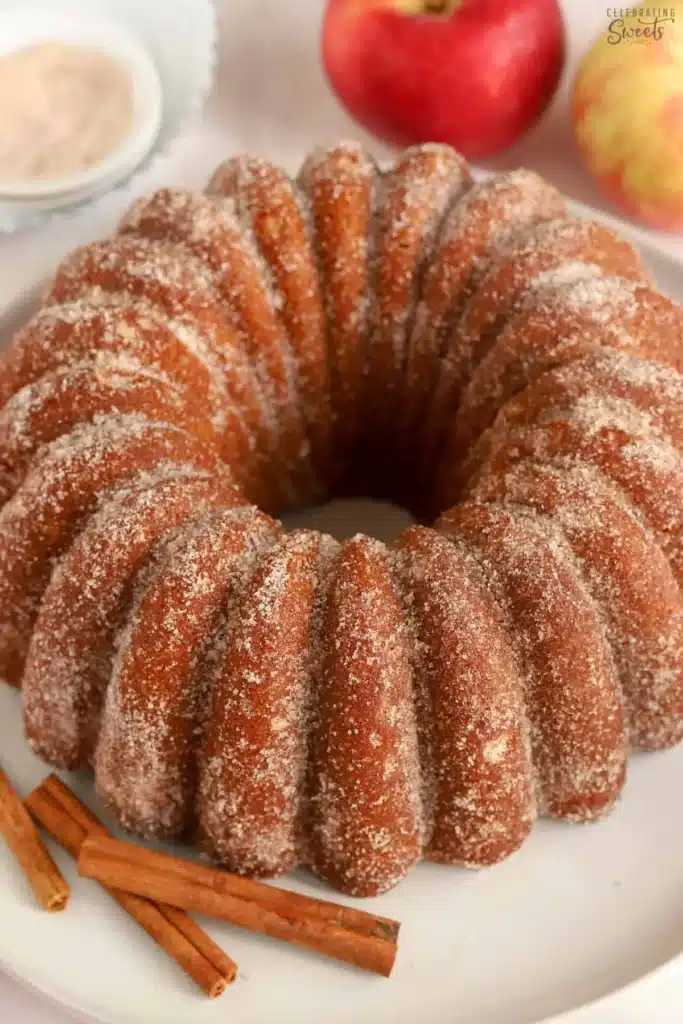 Home 7 Apple Cider Donut Cake moist fall 9x13 snack cake with silky cinnamon cream cheese frosting in a white baking dish on marble with apple cider alongside