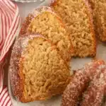 A rectangle of Apple Cider Donut Cake showing the moist apple cider spiced crumb with silky cinnamon cream cheese frosting on a white plate