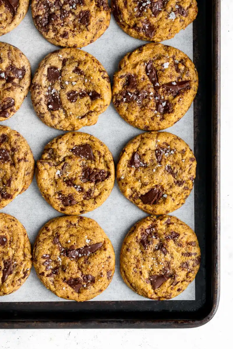 Home 3 Chewy Pumpkin Chocolate Chip Cookie golden thick fall cookies with chocolate chips and flaky sea salt on a white plate on marble