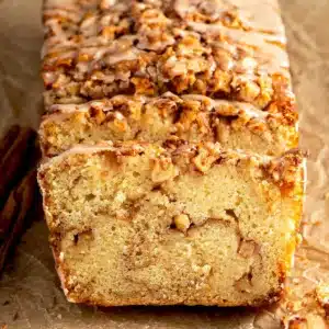 Cinnamon Apple Bread beautiful moist fall quick bread loaf with gorgeous cinnamon swirl visible on a white cutting board on marble with fresh apples alongside
