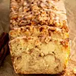 A slice of Cinnamon Apple Bread showing the moist brown sugar oil crumb with gorgeous brown sugar cinnamon swirl ribbon and fresh apple pieces on a white plate