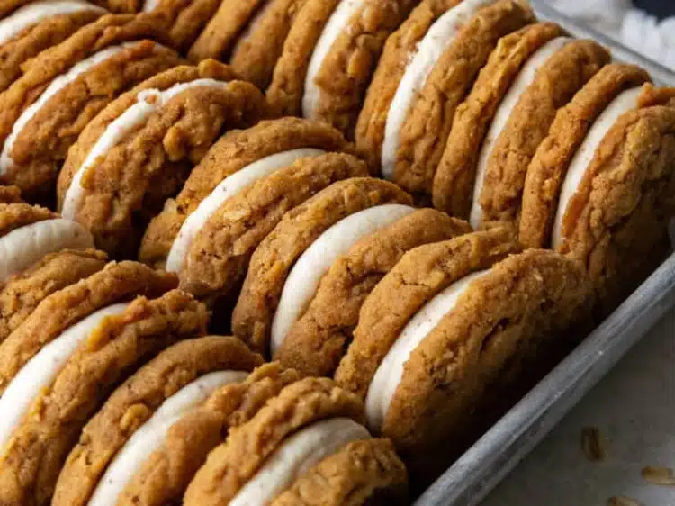 Oatmeal Sandwich Cookies beautiful chewy oat sandwich cookies with silky cream cheese cinnamon filling visible from the side on a white plate on marble