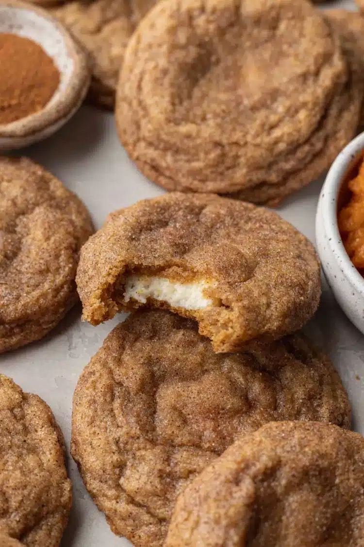 Home 3 Pumpkin Cheesecake Cookies gorgeous fall cookies with cinnamon-pumpkin spice sugar coating broken open to reveal the smooth cream cheese cheesecake center on a white plate on marble