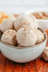 Apple Pie Truffles gorgeous no-bake fall truffles with white chocolate coating graham cracker crumb garnish cinnamon dusting and caramel drizzle on a white plate on marble