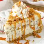 A slice of Browned Butter Pecan Cheesecake showing the toasted pecan graham crust smooth brown butter filling and warm caramel pecan topping on a white plate