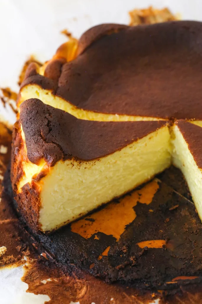 Home 4 Burnt Basque Cheesecake dramatic crustless cheesecake with deeply dark caramelized almost-burnt top and custardy creamy interior on parchment on a white plate on marble