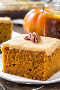 Pumpkin Cake with Caramel Cream Cheese Frosting stunning two-layer fall celebration cake with dramatic caramel drip and optional flaky sea salt on a white cake stand on marble